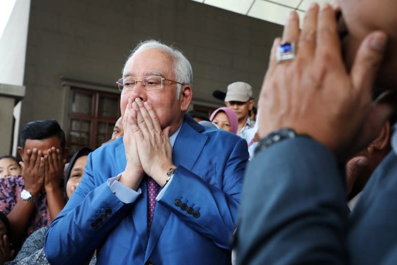 Former Malaysian Prime Minister Najib Razak prays with his supporters before entering a court room at Kuala Lumpur High Court