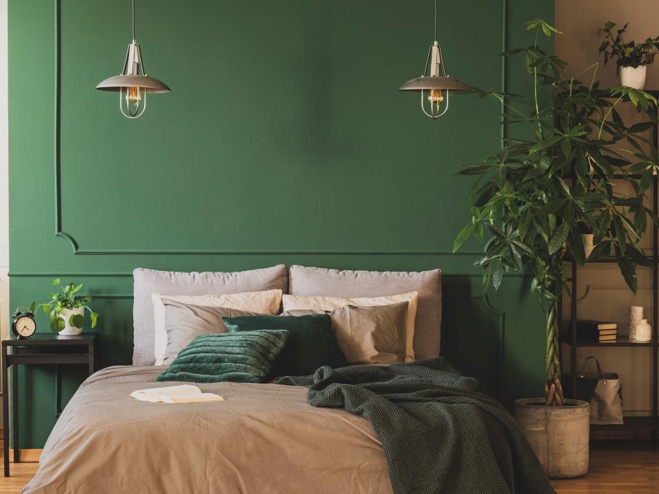 Green wall in bedroom and bed with gray sheets