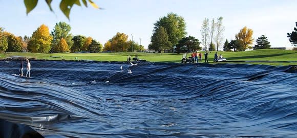 An empty golf course pond with black lining installed.