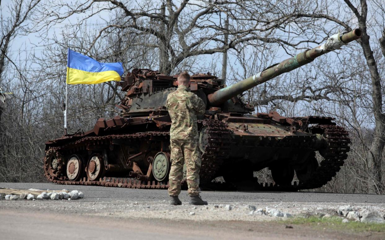 A Ukrainian serviceman stands next to a Ukrainian tank destroyed in 2014 by Russia backed separatists, on the front line near the small town of Pisky, Donetsk region - ALEKSEY FILIPPOV/AFP via Getty Images