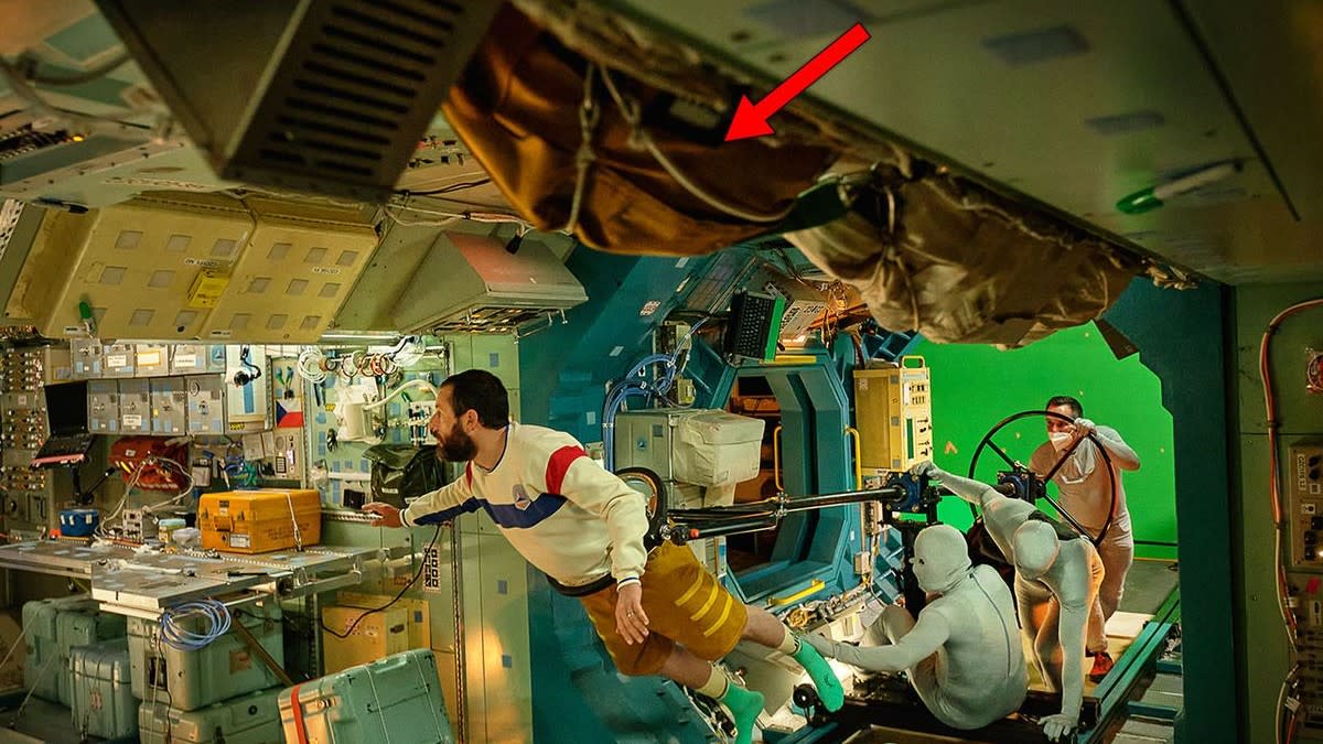  On a movie set, an actor is held aloft by a crane to make him look as if he was floating in a cramped space station corridor. 