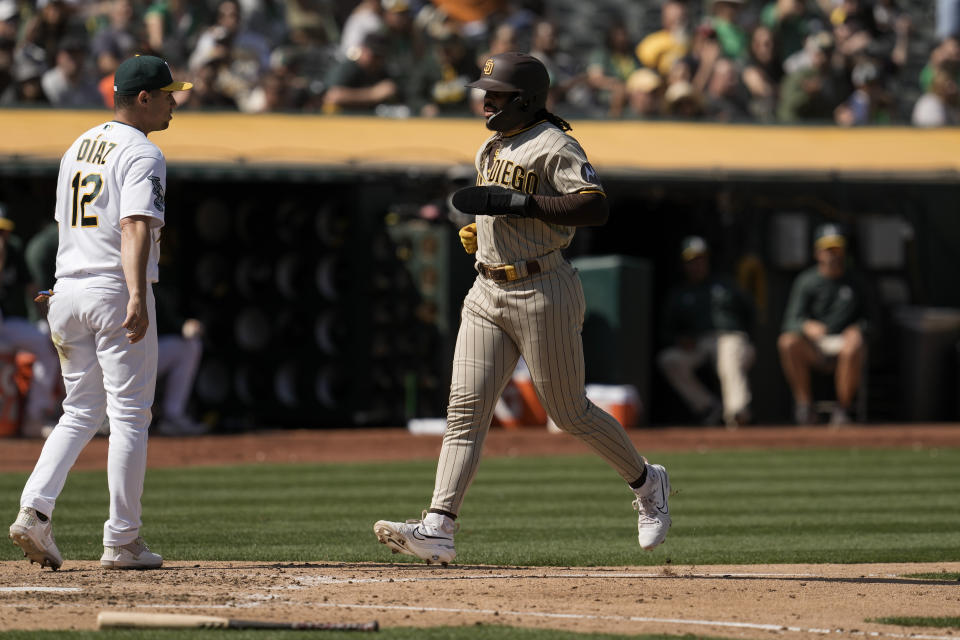 San Diego Padres' Trent Grisham, right, scores against the Oakland Athletics on a throwing error by first baseman Ryan Noda during the fifth inning of a baseball game, Saturday, Sept. 16, 2023, in Oakland, Calif. Trent Grisham also scored and Brett Sullivan reached first on the play. (AP Photo/Godofredo A. Vásquez)