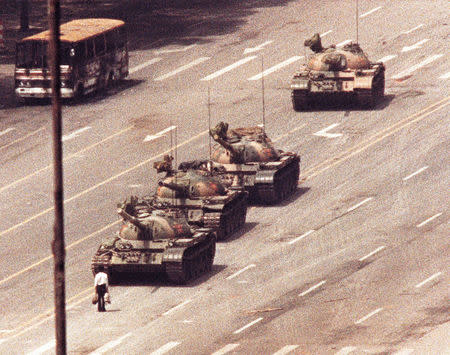 FILE PHOTO: A man stands in front of a convoy of tanks in the Avenue of Eternal Peace in Beijing, China, June 5, 1989. REUTERS/Arthur Tsang/Files