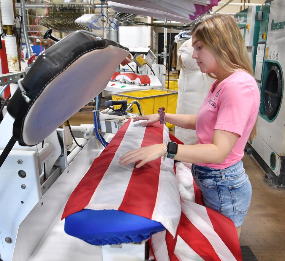 Pressed Dry Cleaners offer a free flag cleaning service. Manager Kaylie Lange straightens one before pressing it.