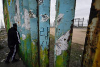 A man looks through the first wall at Friendship Park, near where the border separating Tijuana, Mexico, and San Diego meets the Pacific Ocean Tuesday, Jan. 19, 2021, in Tijuana, Mexico. In the days before Joe Biden became president, construction crews worked quickly to finish Donald Trump's wall at an iconic cross-border park overlooking the Pacific Ocean that then-first lady Pat Nixon inaugurated in 1971 as symbol of international friendship. (AP Photo/Gregory Bull)