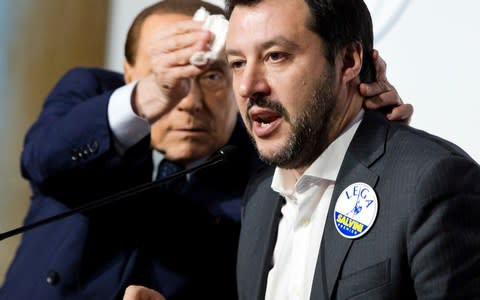 Former prime minister Berlusconi wipes the forehead of Matteo Salvini, the leader of The League Party at a media event  - Credit: AP