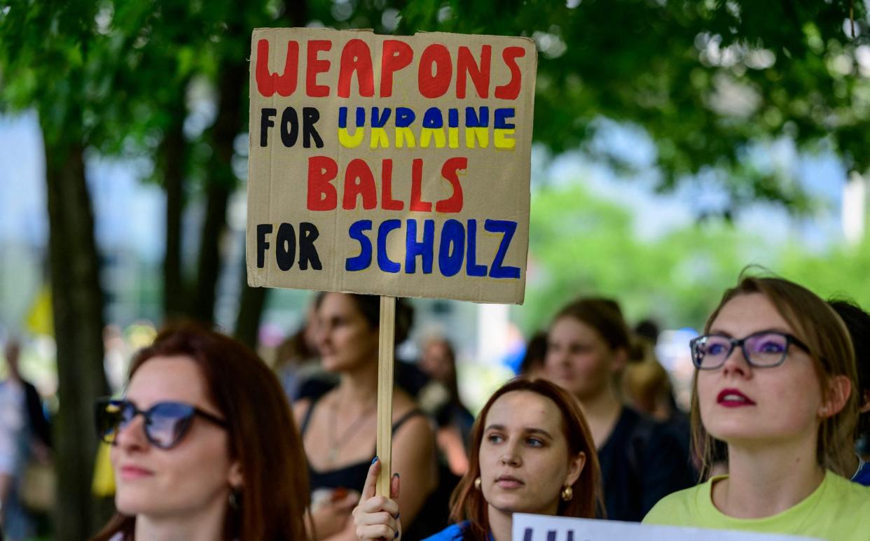 A woman displays a placard reading 'Weapons for Ukraine - balls for Scholz' during a demonstration to thank Germany for its support of Ukraine in Berlin - JOHN MACDOUGALL 