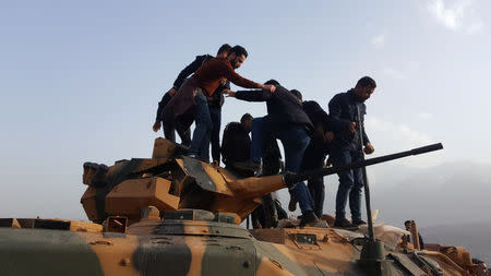 Protesters stand on a Turkish tank after they stormed a Turkish military camp near Dohuk, Iraq January 26, 2019. REUTERS/Stringer