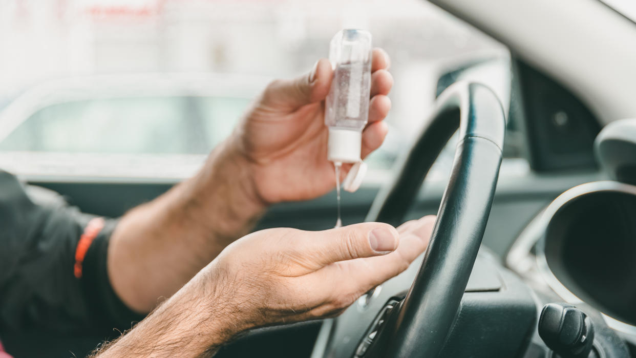 Man using hand sanitizer while sitting in car, he is cleaning her hands after shopping.