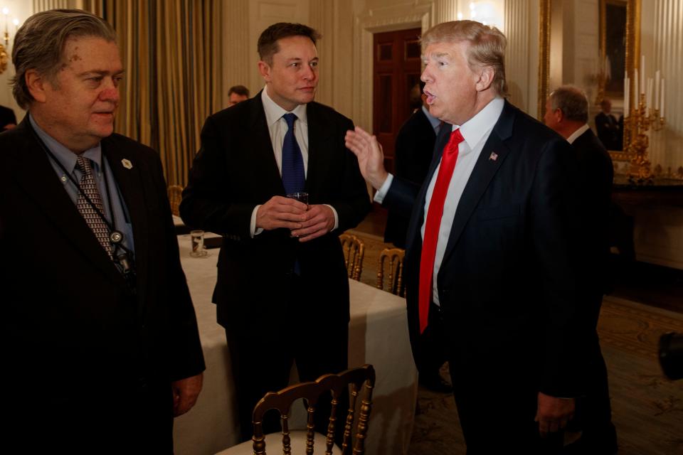 President Donald Trump talks with Tesla and SpaceX CEO Elon Musk, center, and White House chief strategist Steve Bannon during a meeting with business leaders in the State Dining Room of the White House in Washington on Friday, Feb. 3, 2017.