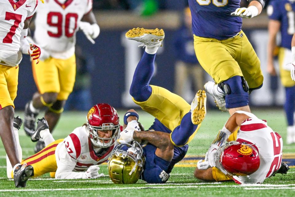 Oct 14, 2023; South Bend, Indiana, USA; Notre Dame Fighting Irish wide receiver Chris Tyree (4) is tackled by USC Trojans safety Bryson Shaw (27) and linebacker Tackett Curtis (25) in the second quarter at Notre Dame Stadium. Mandatory Credit: Matt Cashore-USA TODAY Sports
