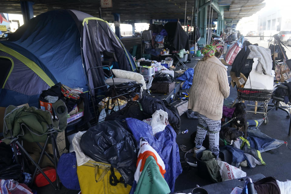 ARCHIVO - Una mujer recoge sus pertenencias antes de las tareas de retiro de un campamento de desamparados en San Francisco, el 29 de agosto de 2023. (AP Foto/Jeff Chiu, archivo)