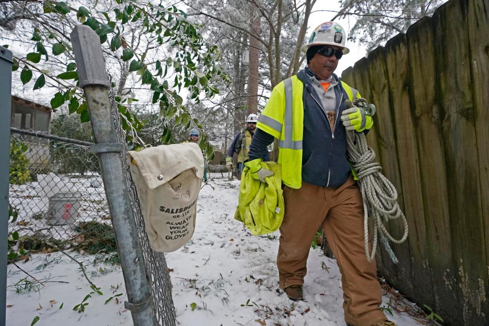 Lineman Harold Armstrong carries ropes to a truck as he and other electrical specialists repair a transformer in Jackson, Miss., Thursday, Feb. 18, 2021.