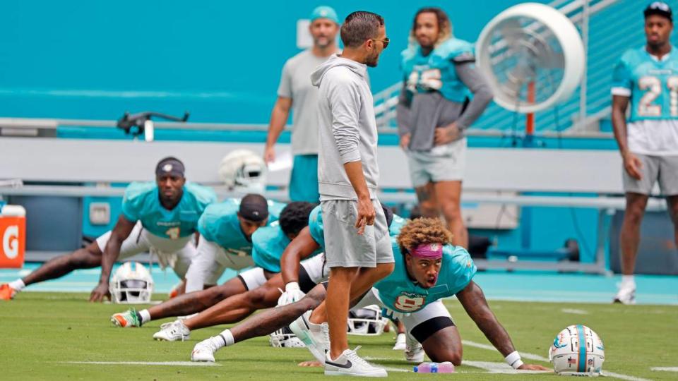 Miami Dolphins coach Mike McDaniel walks past safety Jevon Holland (8) during stretches at a team scrimmage at Hard Rock Stadium in Miami Gardens on Saturday, August 5, 2023.