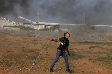 A Palestinian boy hurls stones at Israeli troops during a protest calling for lifting the Israeli blockade on Gaza and demand the right to return to their homeland, at the Israel-Gaza border fence, east of Gaza City September 14, 2018. REUTERS/Mohammed Salem