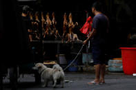 A man walks with his pet dog as he talks to a vendor selling dog meat at a market during the local dog meat festival in Yulin, Guangxi Autonomous Region, China June 21, 2018. REUTERS/Tyrone Siu