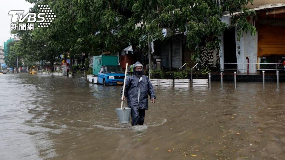 孟買民眾穿戴著雨衣、口罩在風雨中做好防疫措施(圖／達志影像美聯社)