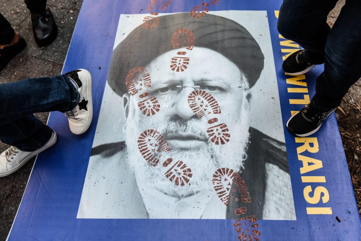 People step on a poster of Iranian President Ebrahim Raisi