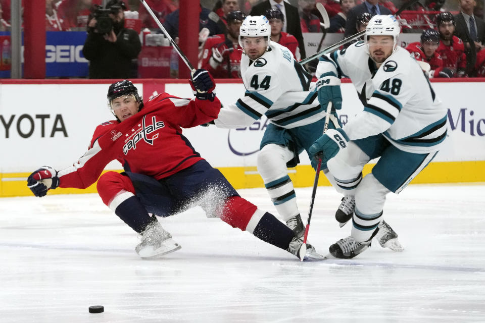 Washington Capitals right wing T.J. Oshie (77), San Jose Sharks defenseman Marc-Edouard Vlasic (44) and Sharks center Tomas Hertl (48) battle for control of the puck in the first period of an NHL hockey game, Sunday, Oct. 29, 2023, in Washington. (AP Photo/Mark Schiefelbein)