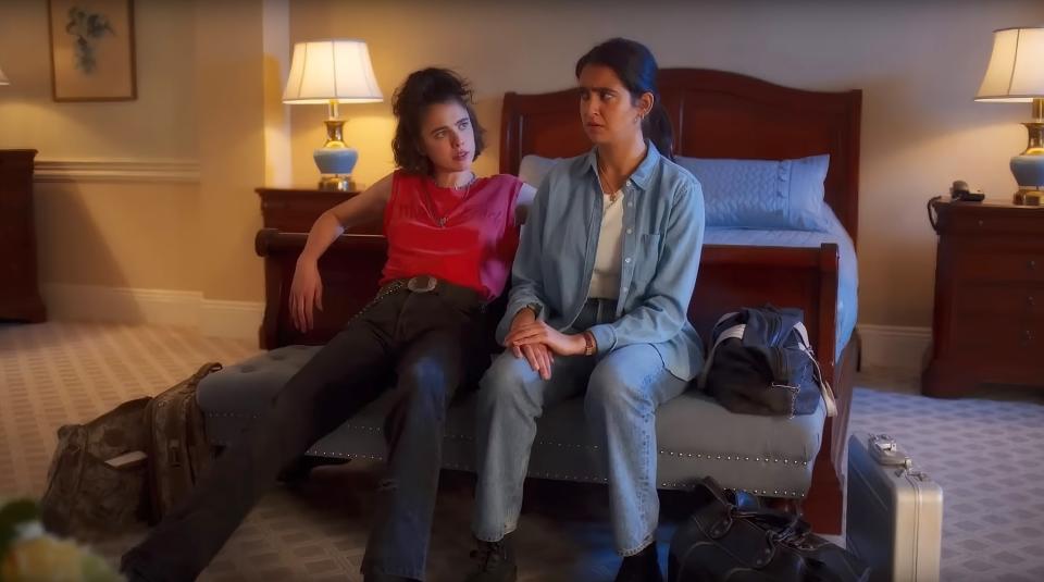 Jamie and Marian sitting in front of a bed in a scene from "Drive-Away Dolls"