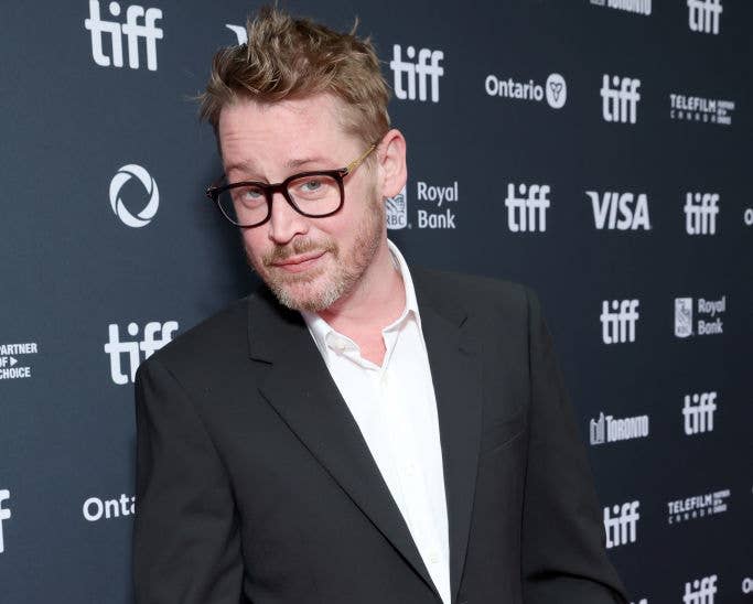 Macaulay Culkin poses on the red carpet in a black suit with a white shirt at the Toronto International Film Festival (TIFF) event