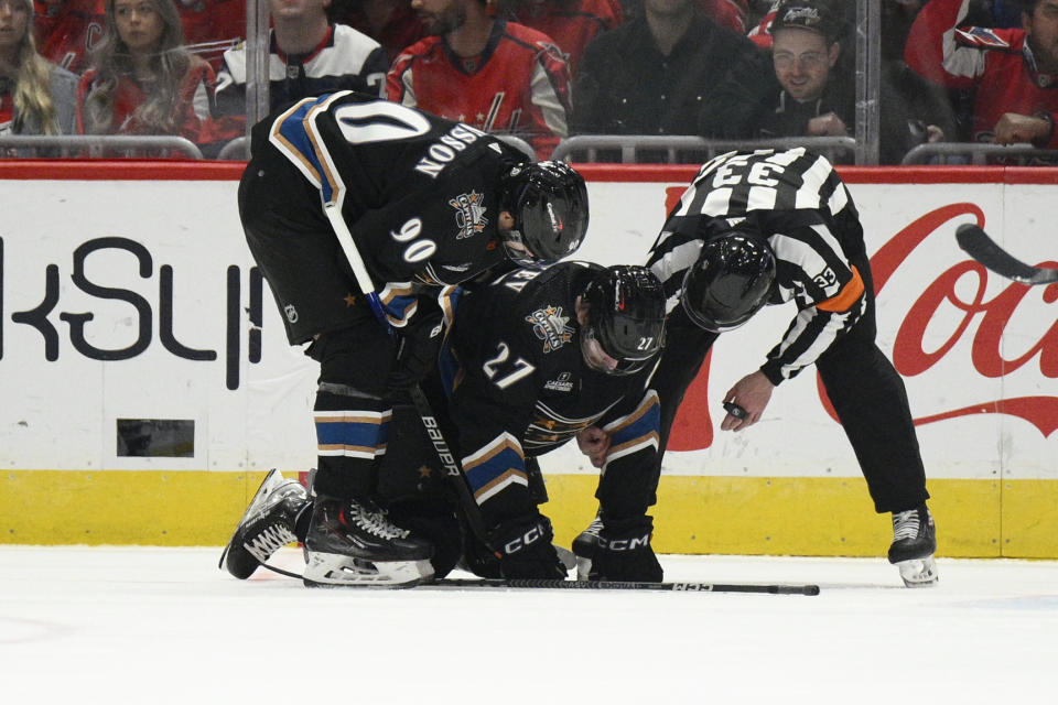 Washington Capitals defenseman Alexander Alexeyev (27) is tended to by left wing Marcus Johansson (90) after he was hit by Seattle Kraken defenseman Jamie Oleksiak during the second period of an NHL hockey game, Friday, Dec. 9, 2022, in Washington. (AP Photo/Nick Wass)