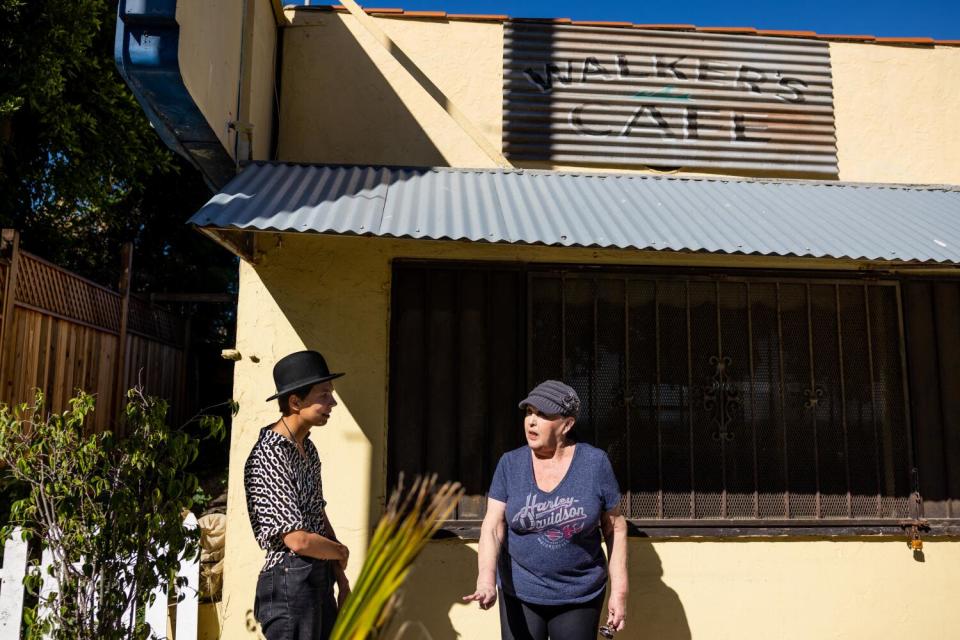 Two women speak while standing outside the Walker's Cafe building.