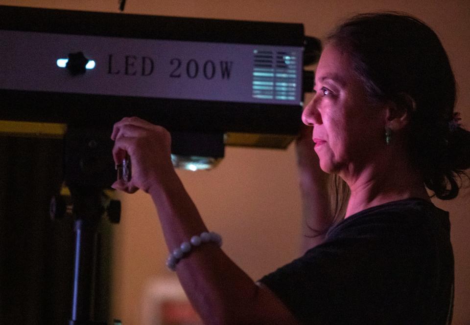 Green Room Theatre President Karen Lin takes video on her phone while operating one of the spotlights during a reading of Shakespeare's As You Like It at The Joslyn Center in Palm Desert, Calif., Thursday, Sept. 28, 2023. The theater is currently staging a traveling production of "Maggie Magalita" every weekend in March.