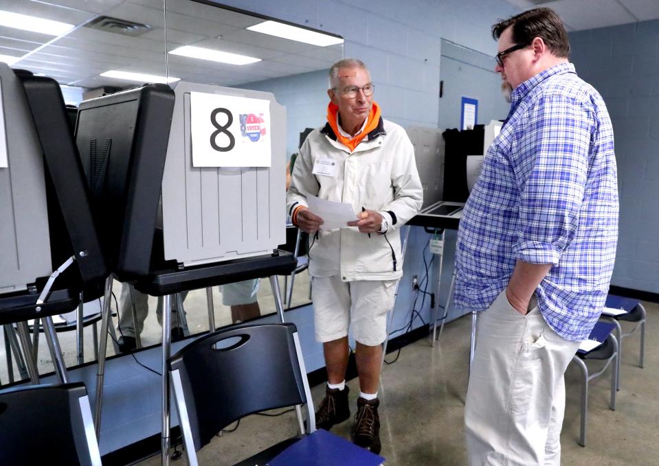 Gary Johnson, sets left William Startling, right, up to vote at a machine at SportsCom on the first day of early voting on Wednesday, Oct. 19, 2022.