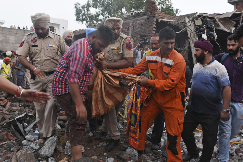 Rescuers carry the body of a victim at the site of an explosion at a fireworks factory in Batala, in the northern Indian state of Punjab, Wednesday, Sept. 4, 2019. More than a dozen people were killed in the explosion that caused the building to catch fire and collapse, officials said. (AP Photo/Prabhjot Gill)