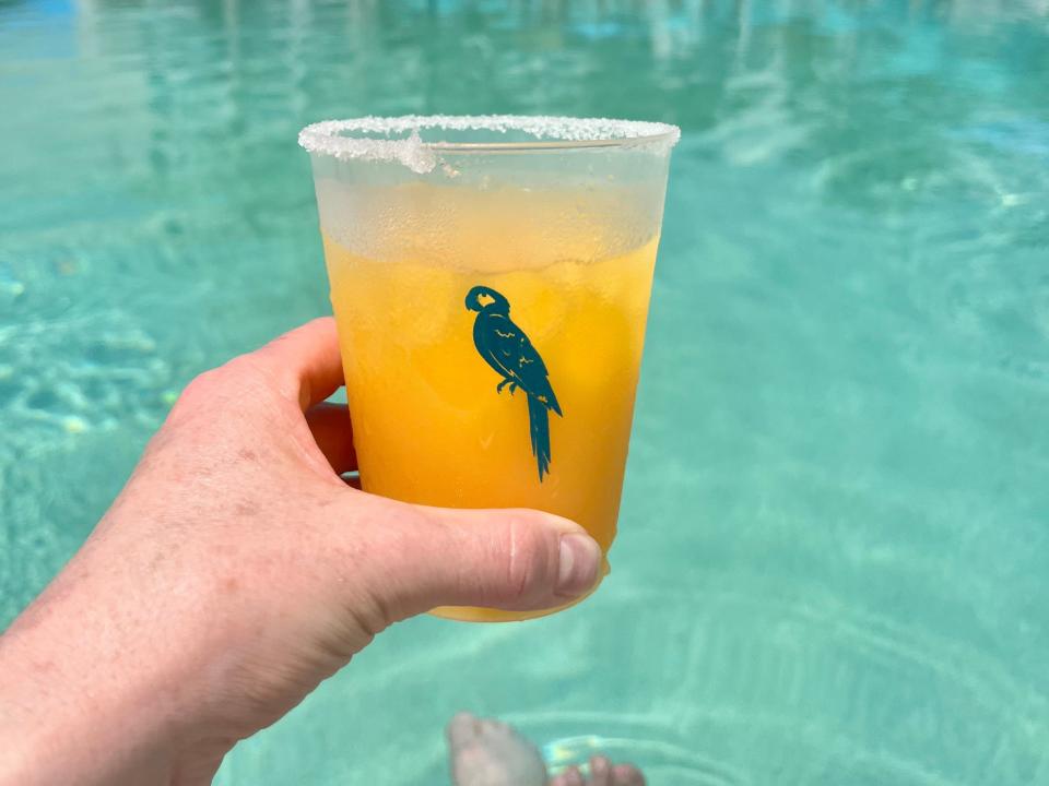 hand holding up a margarita in a pool at a resort