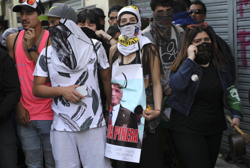 A demonstrator holds a defaced poster of Chile's President Sebastian Pinera during protests in Santiago, Chile, Wednesday, Oct. 23, 2019. Rioting, arson attacks and violent clashes wracked Chile as the government raised the death toll in an upheaval that has almost paralyzed the South American country long seen as the region's oasis of stability. (AP Photo/Rodrigo Abd)