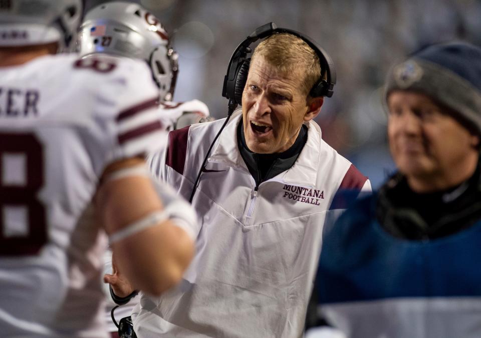 Montana coach Bobby Hauck meets with his players on the sideline during the first half of an NCAA FCS football playoff game against James Madison in Harrisonburg, Va., Friday, Dec. 10, 2021. (Daniel Lin/Daily News-Record via AP)