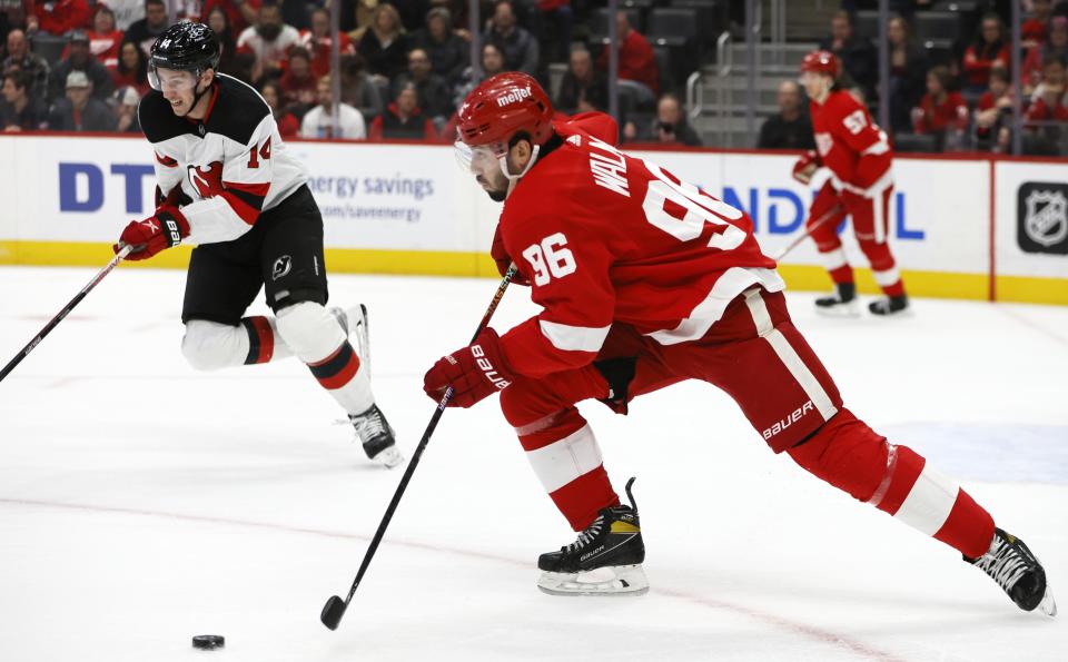 Detroit Red Wings defenseman Jake Walman (96) brings the puck down the ice against New Jersey Devils right wing Nathan Bastian (14) during the first period of an NHL hockey game Wednesday, Nov. 22, 2023, in Detroit. (AP Photo/Duane Burleson)