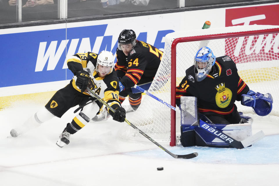 Hamilton Bulldogs' Jan Mysak, left, skates past Saint John Sea Dogs' Jeremy Poirier, center, to try and score on goalie Nikolas Hurtubise during the first period of a Memorial Cup hockey game in Saint John, Canada, on Monday, June 20, 2022. (Darren Calabrese/The Canadian Press via AP)