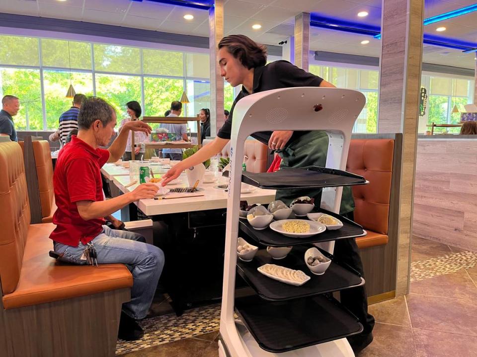 At Yiding Hot Pot, you pick a broth, then load your meal up with ingredients such as noodles, fresh veggies and seafood. When your order is ready, a robot built with shelving moves the plates to your table so you can begin cooking it all together.