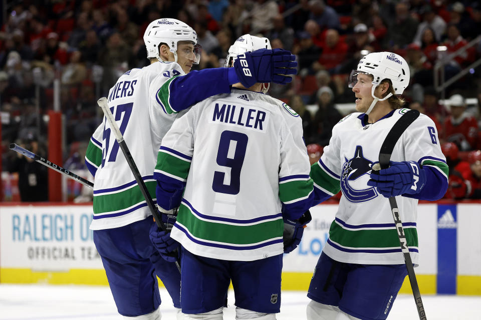 Vancouver Canucks' J.T. Miller (9) is congratulated by Tyler Myers (57) and Brock Boeser (6) for his goal during the third period of the team's NHL hockey game against the Carolina Hurricanes in Raleigh, N.C., Tuesday, Feb. 6, 2024. (AP Photo/Karl B DeBlaker)