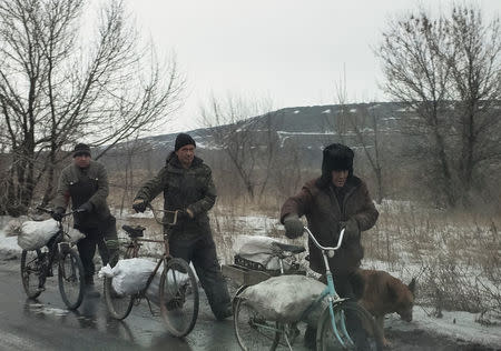 Local residents carry bags containing coal which they collected near a coking plant for heating their homes near the government-held industrial town of Avdiyivka, Ukraine, February 6, 2017. REUTERS/Gleb Garanich