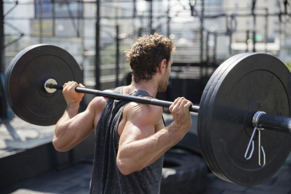 man lifting barbell exercising at rooftop gym