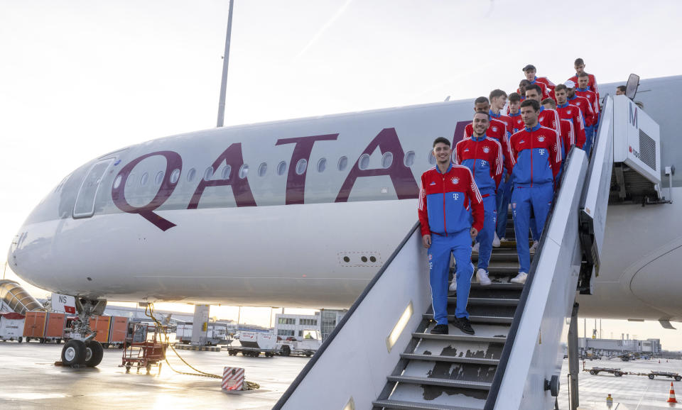 The players of the German Bundesliga team FC Bayern Munich stand on a staircase of an airplane of the airline Qatar Airways at the airport in Munich, Gemany, Friday, Jan. 6, 2023. The Bayern Munich team flies to Qatar on Friday for its winter training camp amid uncertainty over the club’s contentious sponsorship agreement with the Persian Gulf country. (Peter Kneffel/dpa via AP)