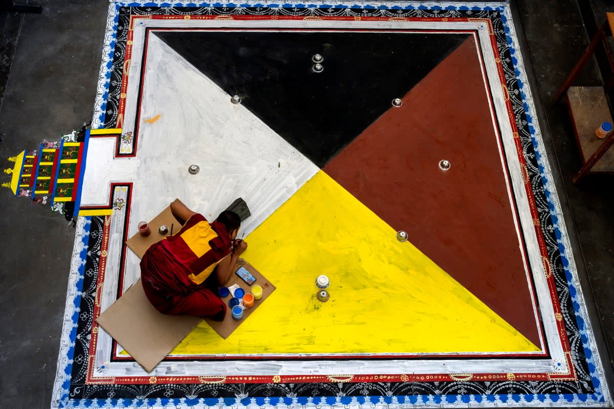 File photo: An exile Tibetan Buddhist monk creates a traditional motif on the floor in preparation for ritual prayers in Dharmsala, India on 20 May (AP)