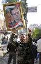 FILE - In this Nov. 20, 2013 file photo, a Syrian soldier holds a portrait of President Bashar Assad, in the town of Hejeira, which Syrian troops captured, in the countryside of Damascus, Syria. As the Syrian conflict entered its forth year this month and large parts of the country are either destroyed or under opposition control, Syrian officials say the presidential elections will be held on time later this year.The opposition rejects such a move saying after the death of more than 140,000 people and millions turned to refugees or displaced, Assad should step down rather than run again. (AP Photo/Jaber al-Helo, File)