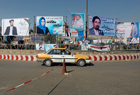 A vehicle drives in front of election posters of parliamentarian candidates installed during the first day of elections campaign in Kabul, Afghanistan September 28, 2018. REUTERS/Omar Sobhani