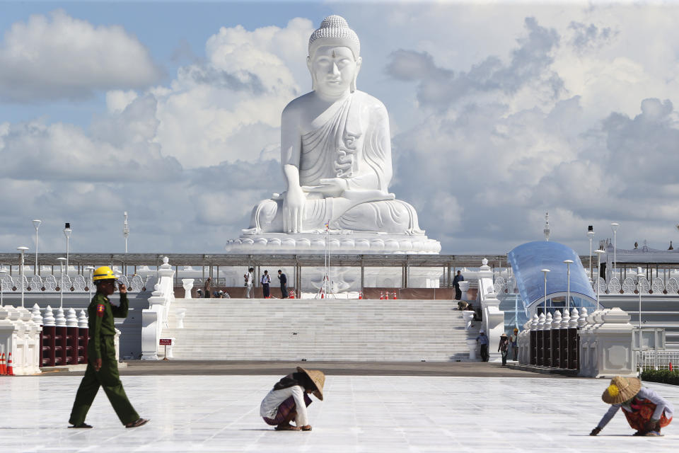 A soldier walks past laborers working below the sitting Maravijaya Buddha marble statue, Friday, July 21, 2023 in Naypyitaw, Myanmar. The Maravijaya Buddha statue is said to be the world’s highest sitting marble Buddha image according to local media. (AP Photo/Aung Shine Oo)