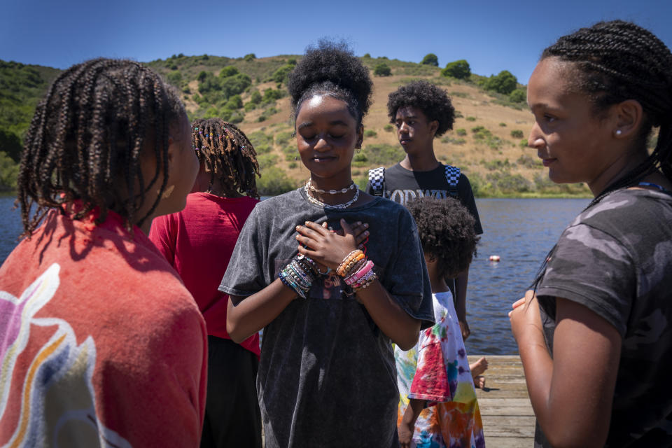Ruby Beerman, 14, center, of Marin County, Calif., who is one of several Ethiopian adoptees attending camp, gestures over her heart while talking with friends at Camp Be'chol Lashon, a sleepaway camp for Jewish children of color, Saturday, July 29, 2023, in Petaluma, Calif., at Walker Creek Ranch. "I get told every day that you're different, you don't belong here, because I'm part of so many different minorities," she said. "And here is kind of a place where everybody belongs to a lot of those minorities. Not everybody is the same here, but we're all different together." (AP Photo/Jacquelyn Martin)