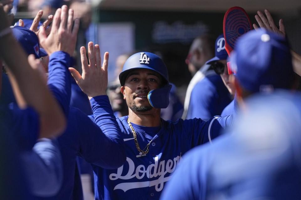 The Dodgers' Mookie Betts high-fives teammates and celebrates after scoring.