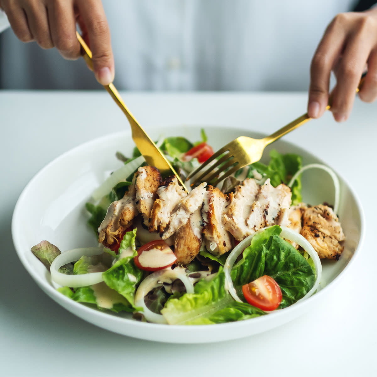 closeup of woman cutting into grilled chicken salad