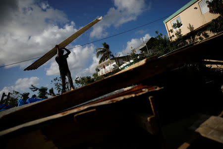 Carlos Ventura carries a corrugated metal sheet to be used for a ceiling, while he helps a neighbour to rebuild her house, which was partially destroyed by Hurricane Maria, at the squatter community of Villa Hugo in Canovanas, Puerto Rico, December 9, 2017. REUTERS/Carlos Garcia Rawlins