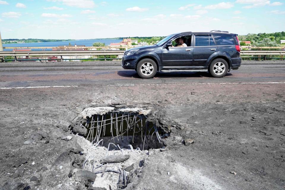 FILE: a car moves past a crater on Kherson’s Antonovsky bridge across the Dnipro (AFP via Getty Images)