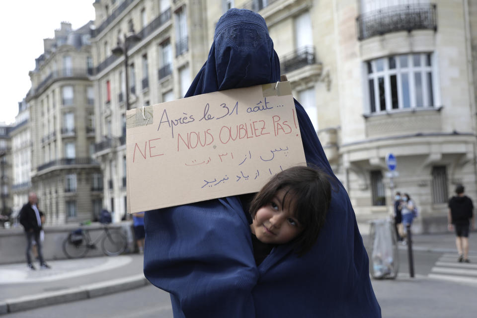 A woman wearing a burqa and holding a poster reading "Do not forget us after Aug.31" attends a gathering in a show of solidarity with women from Afghanistan, Saturday, Aug. 28, 2021 in Paris. France ended evacuation operations on Friday and its team at the makeshift French Embassy at Kabul's airport pulled up stakes. (AP Photo/Adrienne Surprenant)